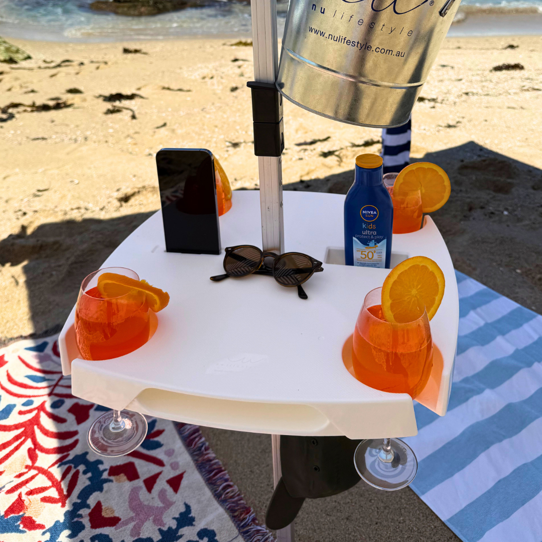 Small table with drinks, phone, and sunglasses on a beach setting
